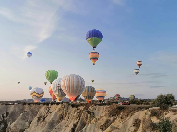 a group of  air balloons flying above the hills