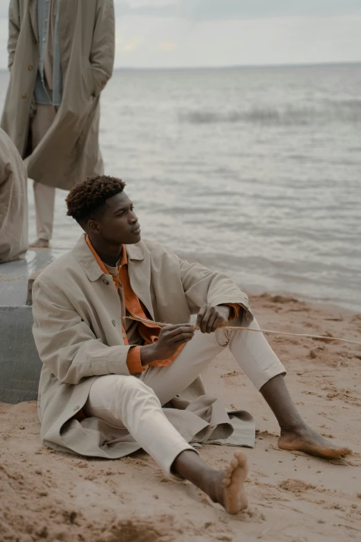 a man is sitting on the beach by some water