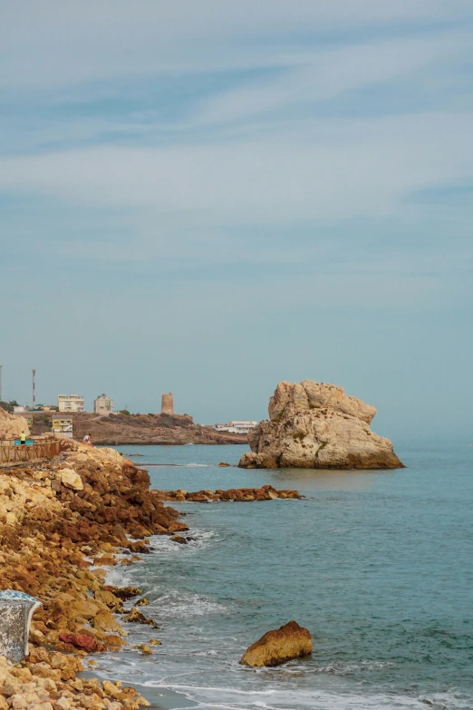 a view of the ocean with rocks and a building on it