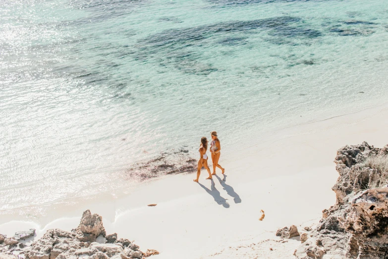 two women are walking along the shore line