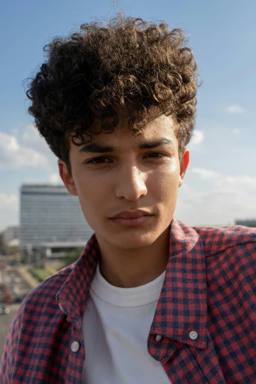 a young man with an afro standing in front of some buildings