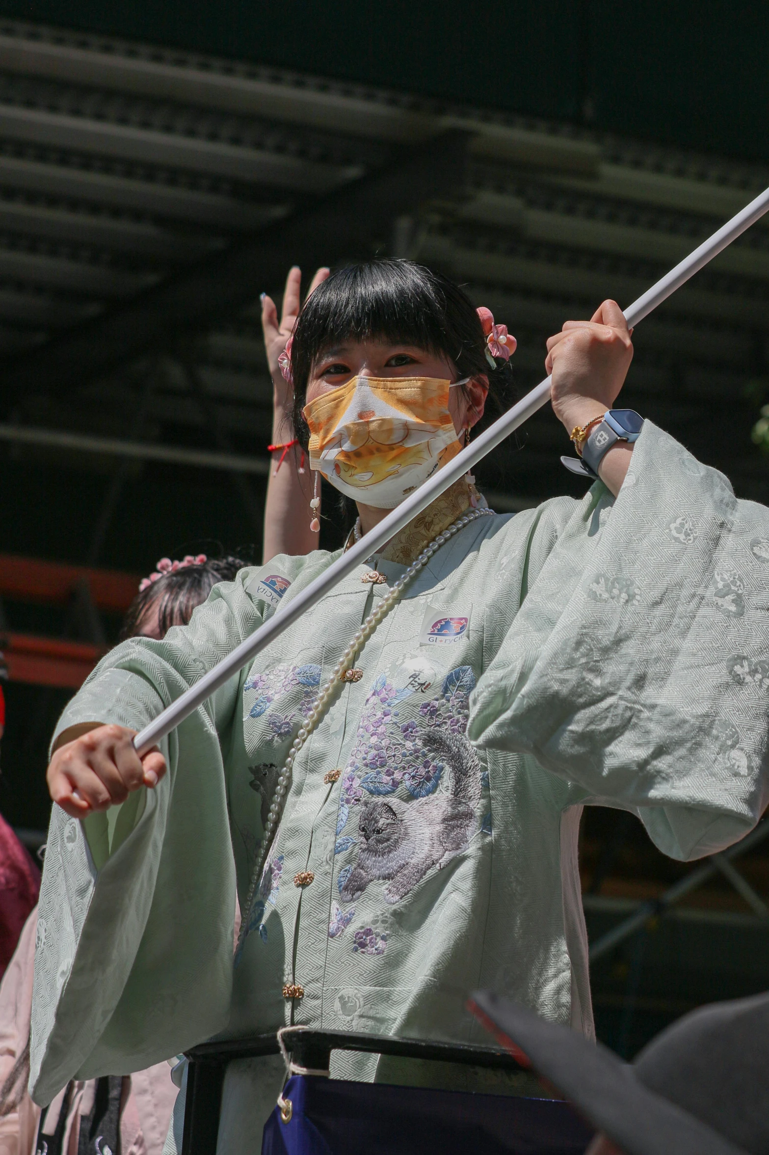 a woman in a white top holds up a long metal pole