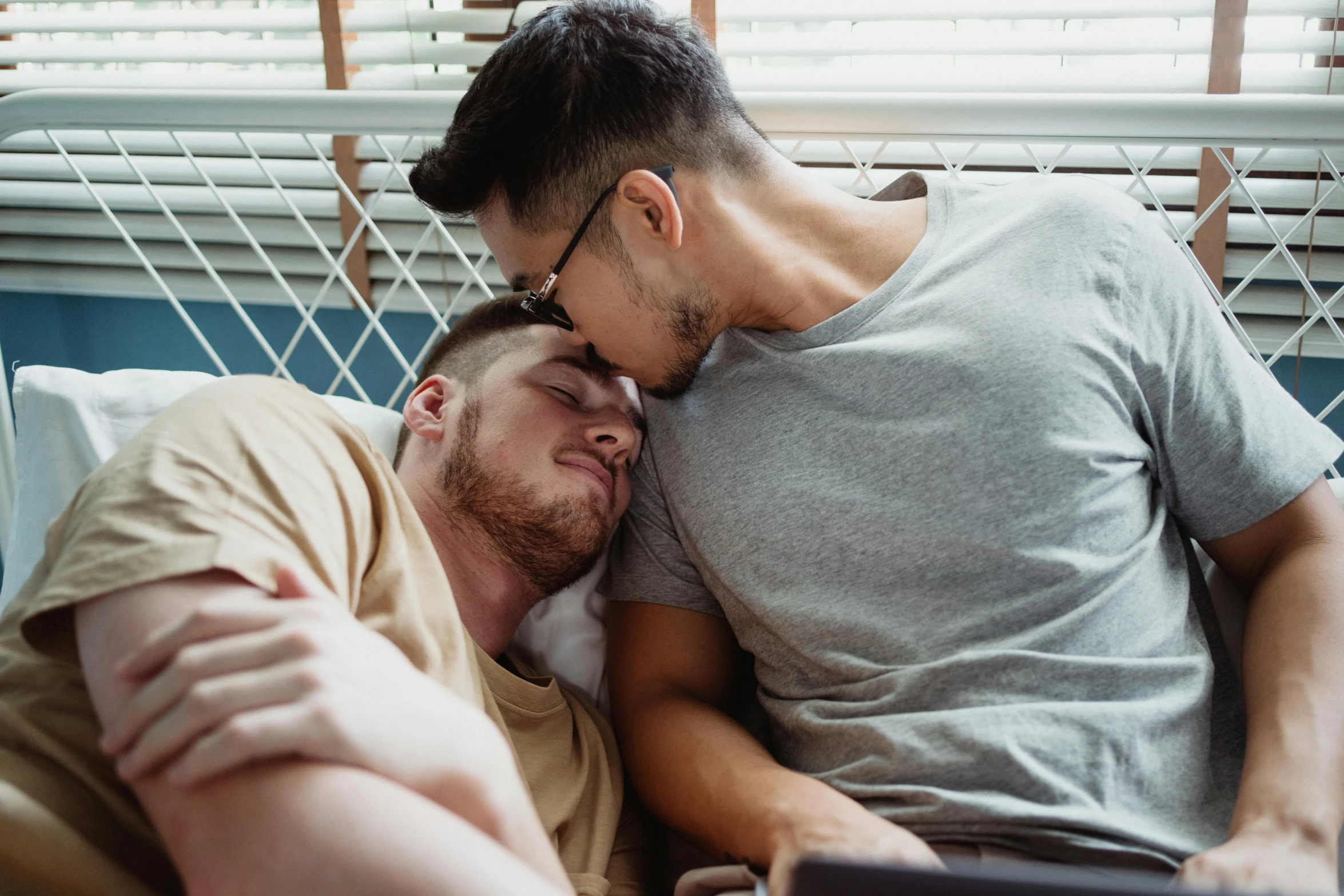 two men in glasses laying down together in bed