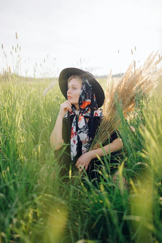 a woman with a hat and floral shirt in tall grass