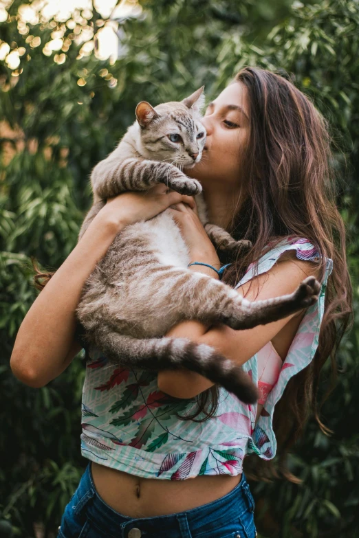 woman holding grey and white cat in her arms outdoors