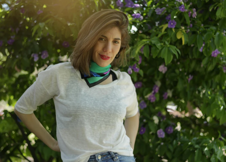 a woman wearing a green bow tie with flowers in the background