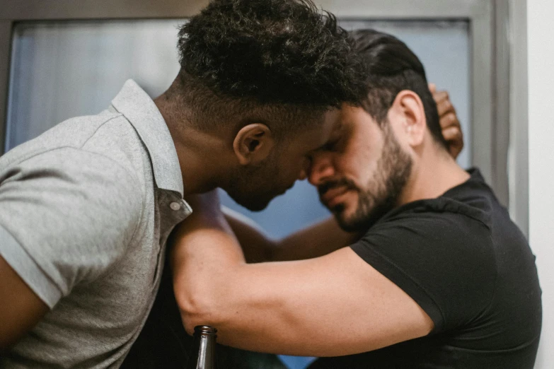 two young men sitting next to each other while leaning on each other