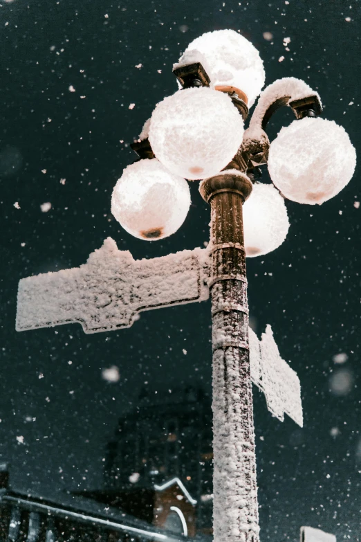 an old fashioned street light covered in snow