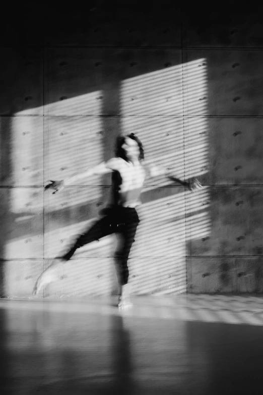 a man dancing in the dark in front of a stone wall