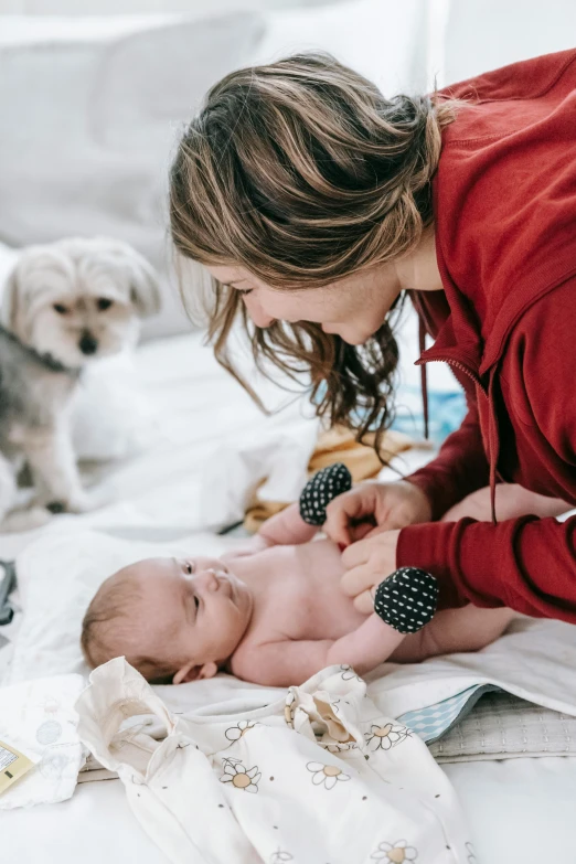 woman putting pacifier on baby while another dog watches