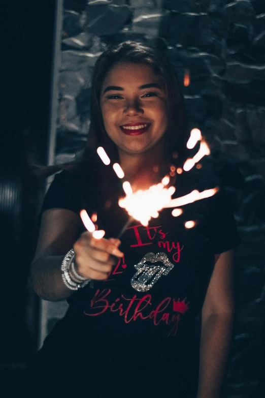 a girl smiles and holds her fingers light up in the air while smiling