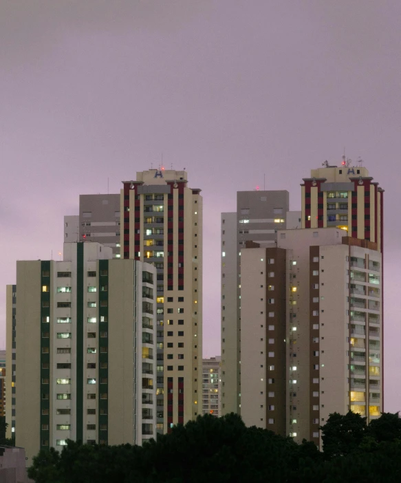 high rise buildings in city lit up against a dark cloudy sky