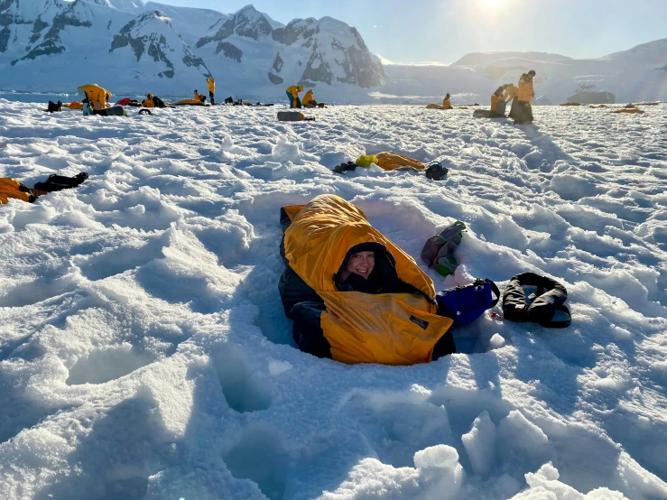 two people on snowboards and some others are sleeping in the snow