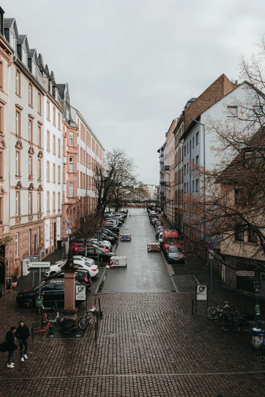 a wide brick walkway lined with rows of parked cars