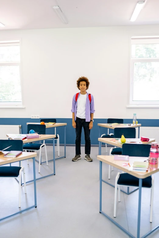 there is a person standing in a classroom at a desk