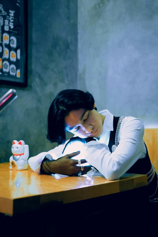 a woman laying her head on the table with an alarm clock beside her