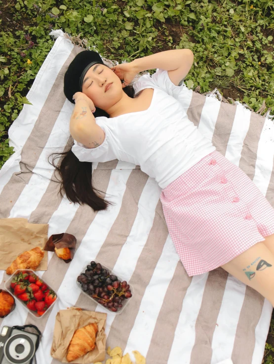 a woman lays on a blanket in the grass