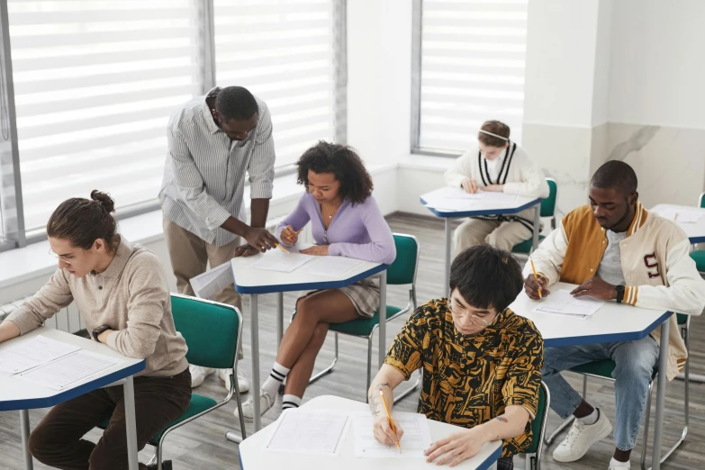 five students sit in chairs in a room together