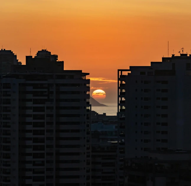 the sun is setting in between tall buildings