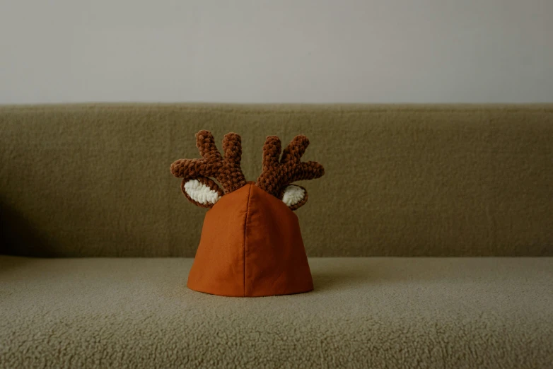 a little deer hat sits on a brown couch