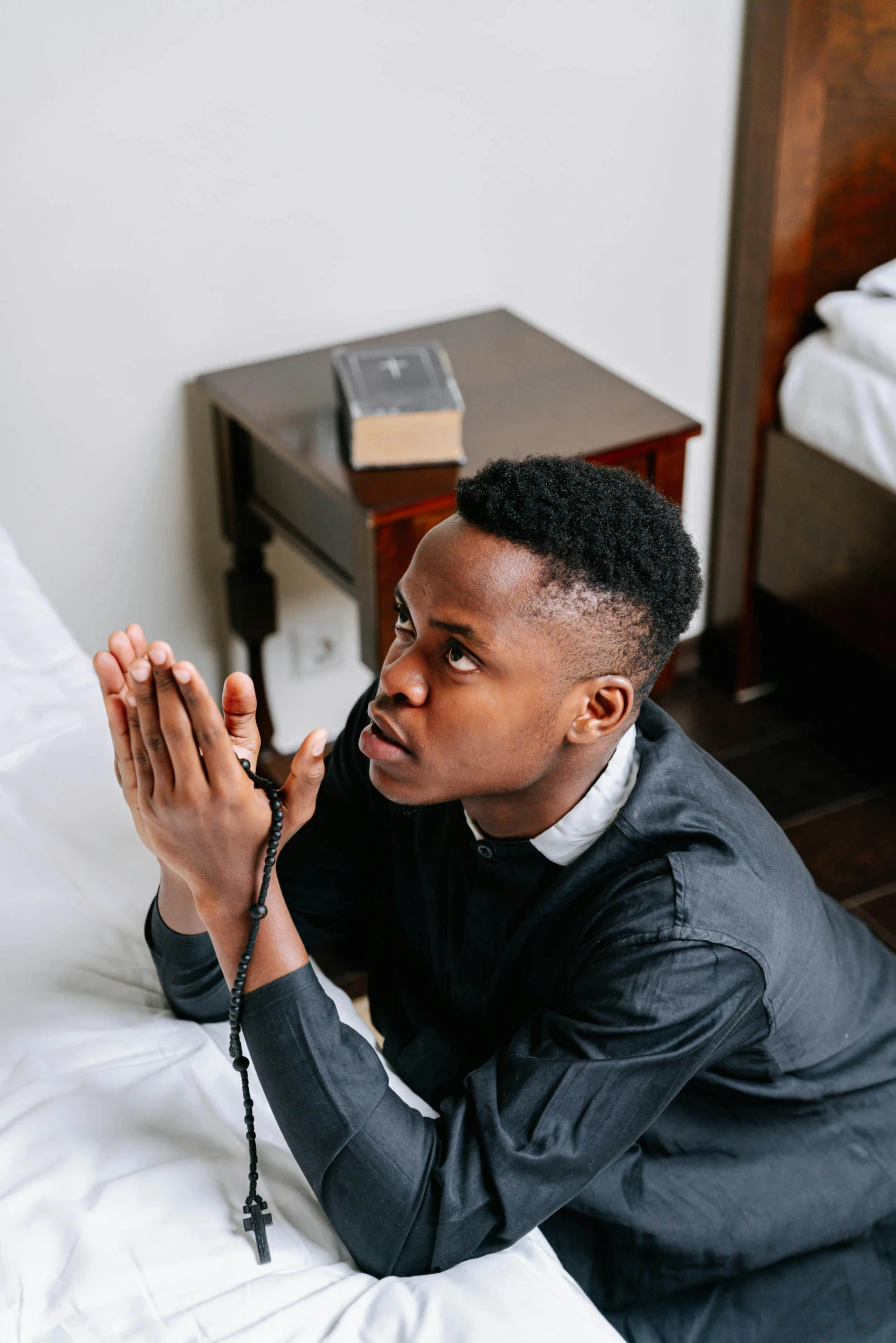 a man wearing a suit is praying on a bed