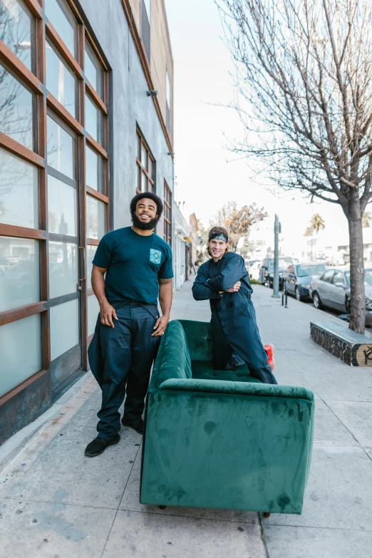 two men pose for the camera in front of a building