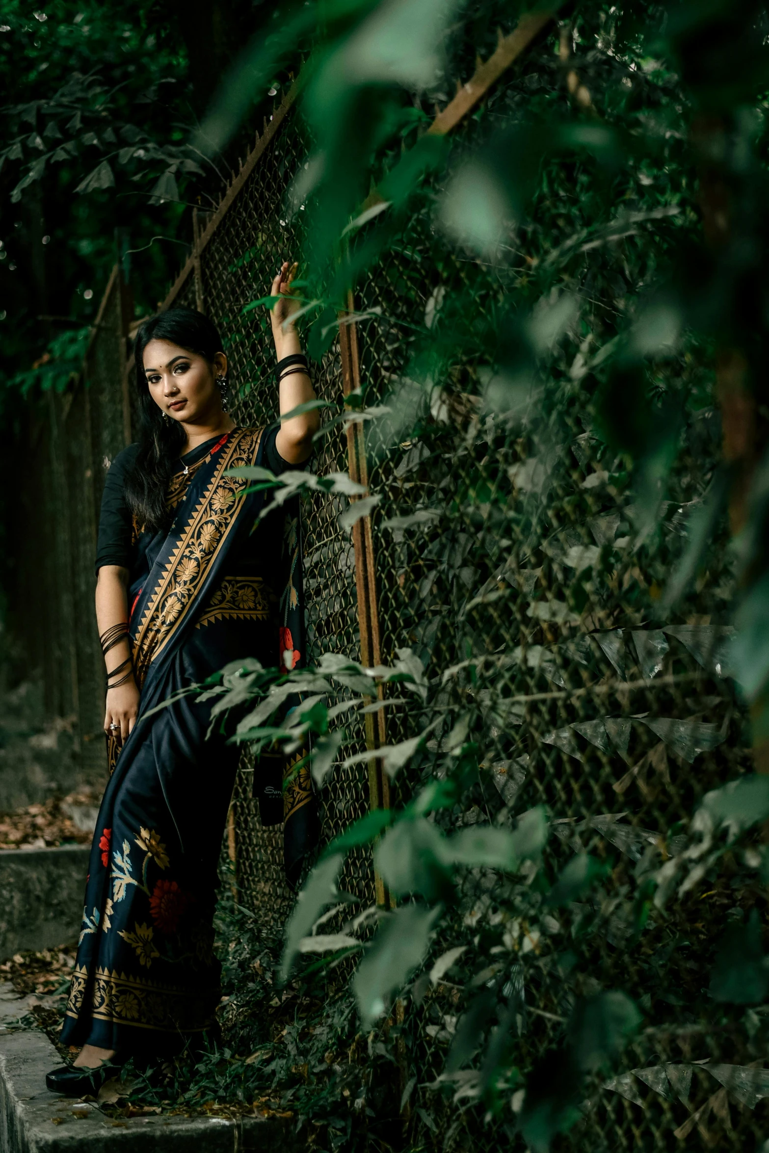 a woman posing in front of some trees