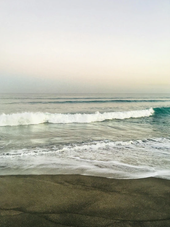 a view from a sandy beach with water waves