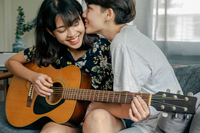 two people kissing and one holding an acoustic guitar