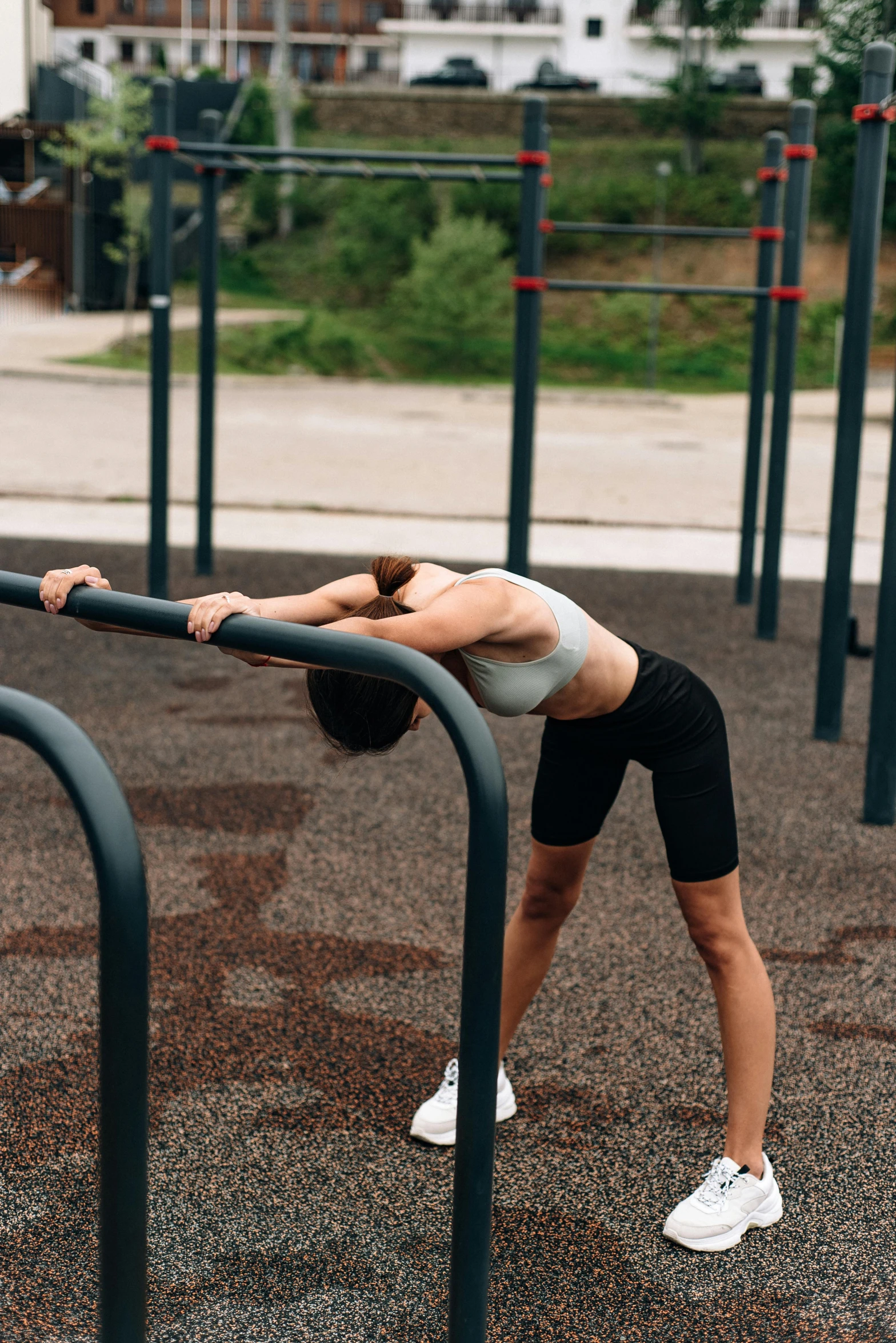 a woman doing yoga in a park on a metal bar