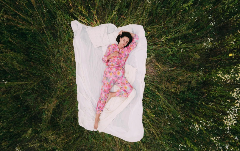 a young woman in pink sleeping bag on grass