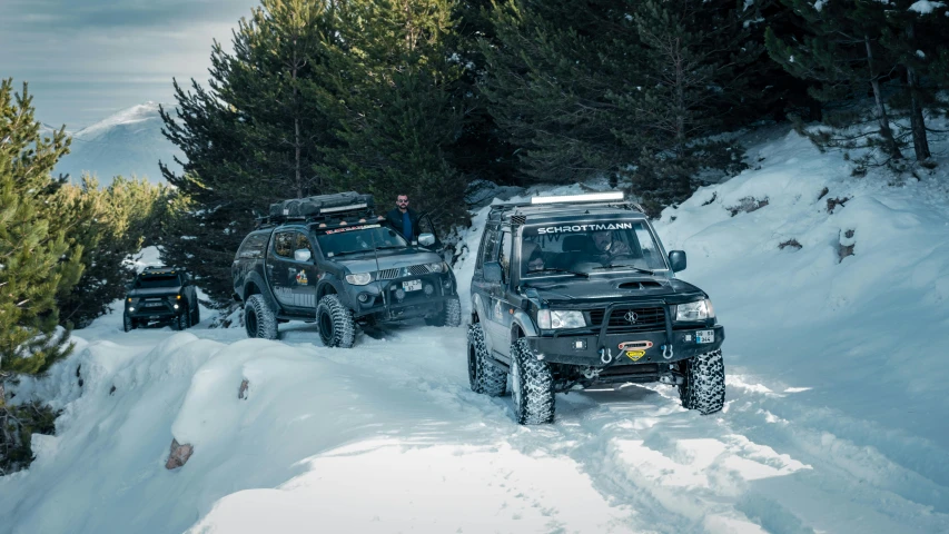 three black off - road vehicles traveling down the snow covered slope