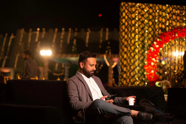 a man sitting on a couch next to a wall with lights on it