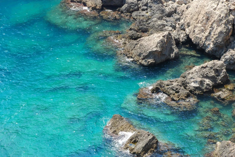 a rocky cliff next to a turquoise water body