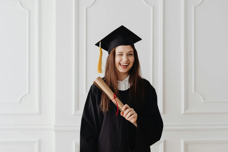 a woman wearing a black graduation gown holding a brown and red diploma