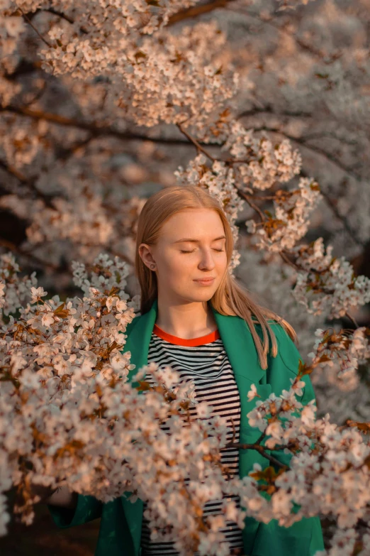 young woman standing under blooming tree with white blossoms