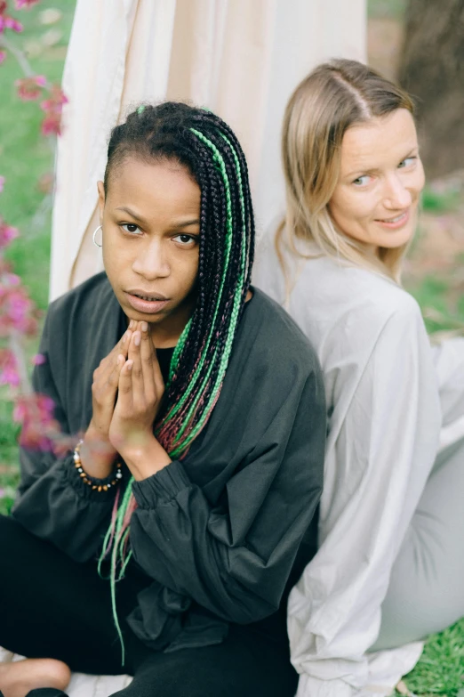 two young women sit and pray in front of flowers