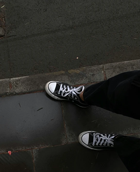 a person is standing on the sidewalk wearing sneakers