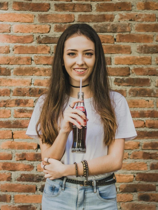 the woman is holding a bottle and wearing a white shirt