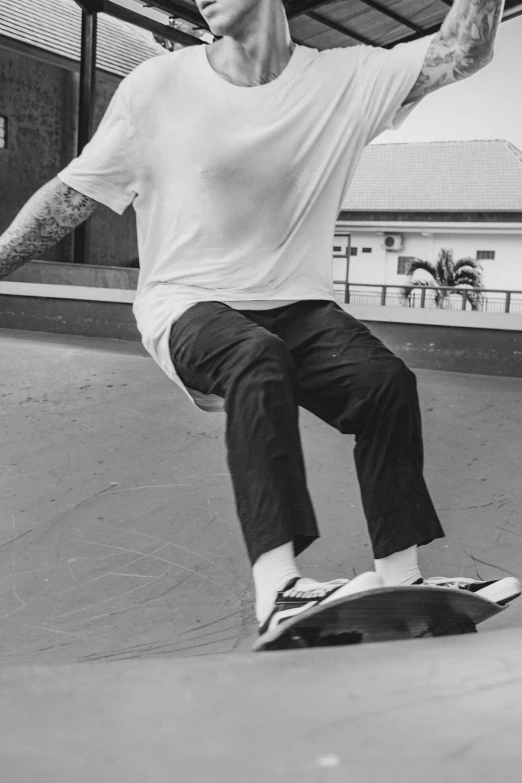 a man with tattooed arms on top of a skateboard
