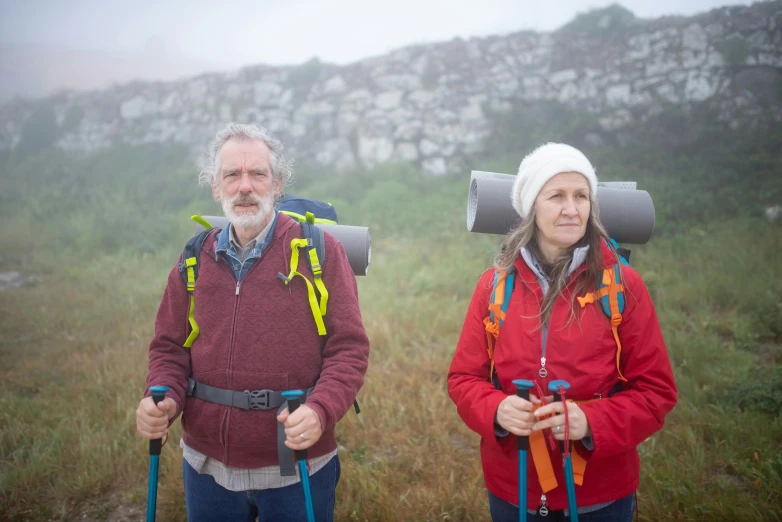 two people walking in a field with backpacks