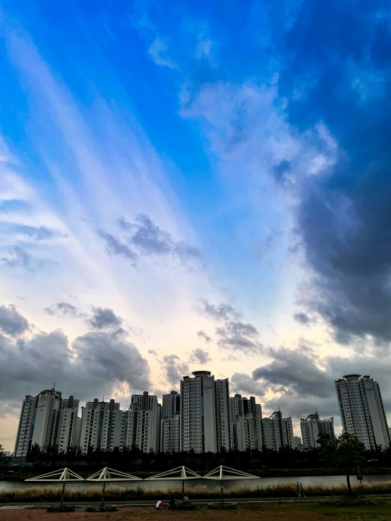 blue cloudy sky over tall buildings and trees