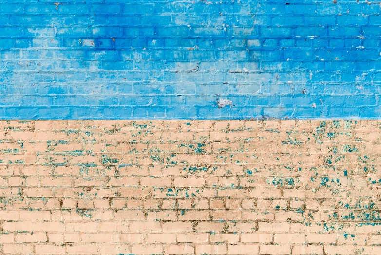 a yellow blue and green bench against a brick wall