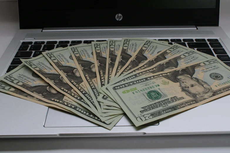a group of money laying on top of a laptop