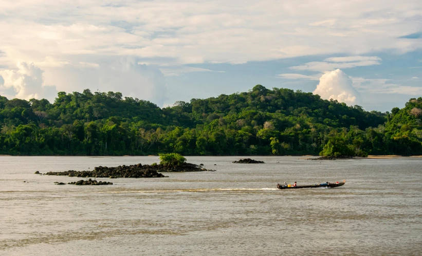 people on boat in large body of water near forested area