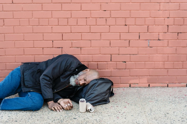 an old man is sleeping next to the wall