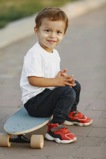 young child sitting on a skateboard on the ground