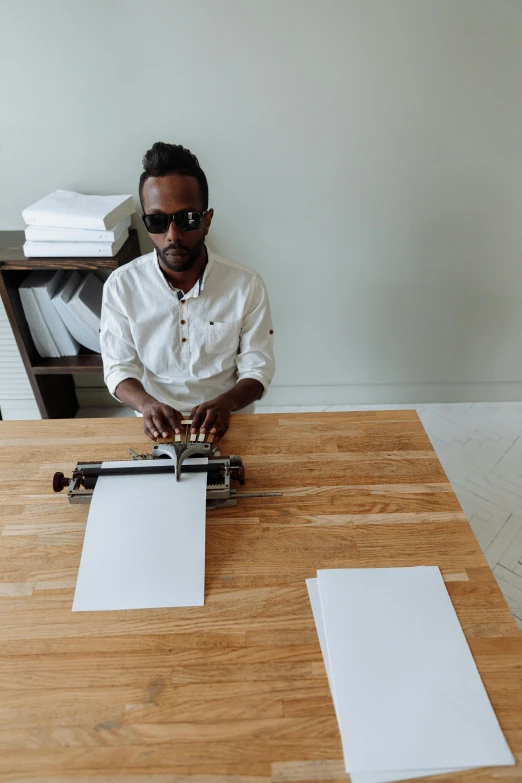 a man in sunglasses sitting at a table making soing