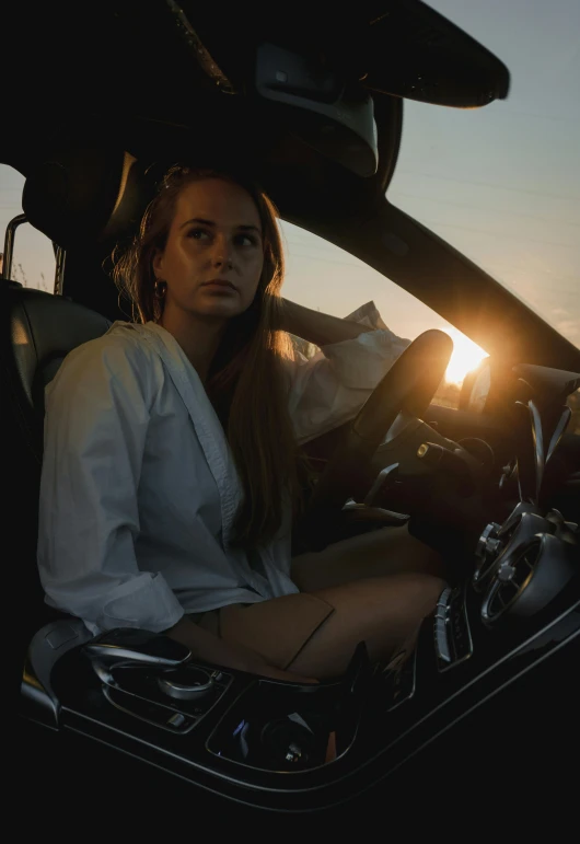 a girl sitting in the back of a car at sunset