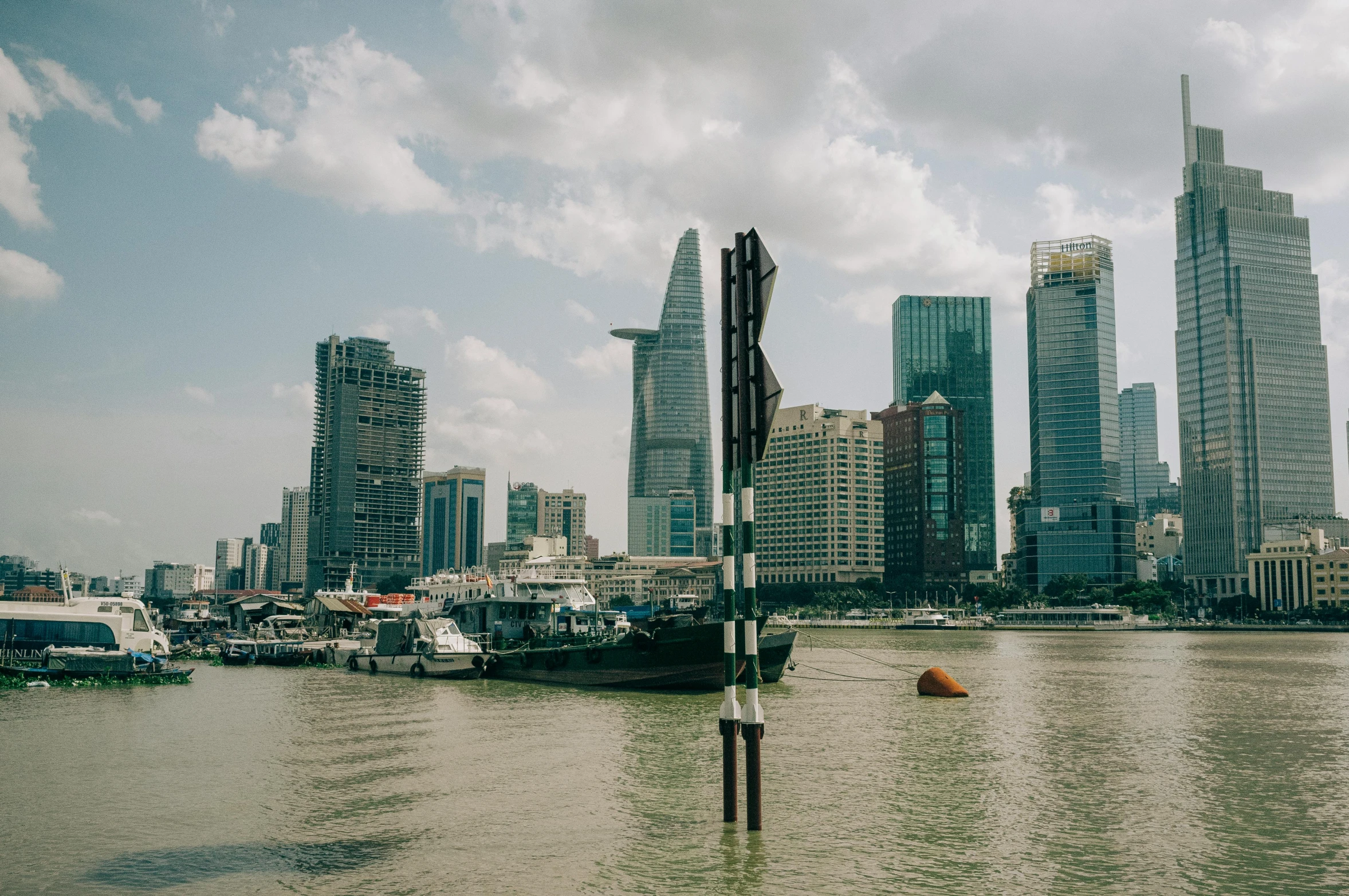 city skyline overlooking river with large boats in front